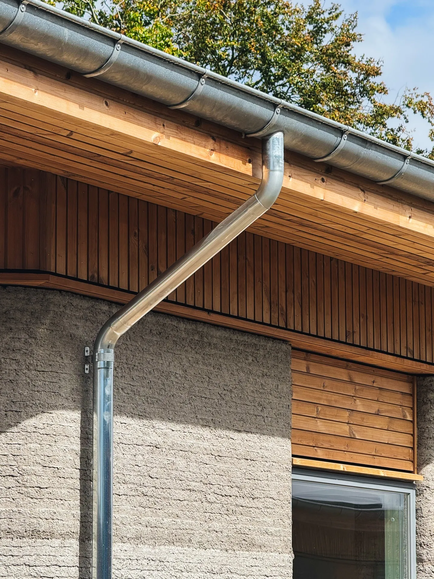 Timber roof edge and downspout above the printed wall